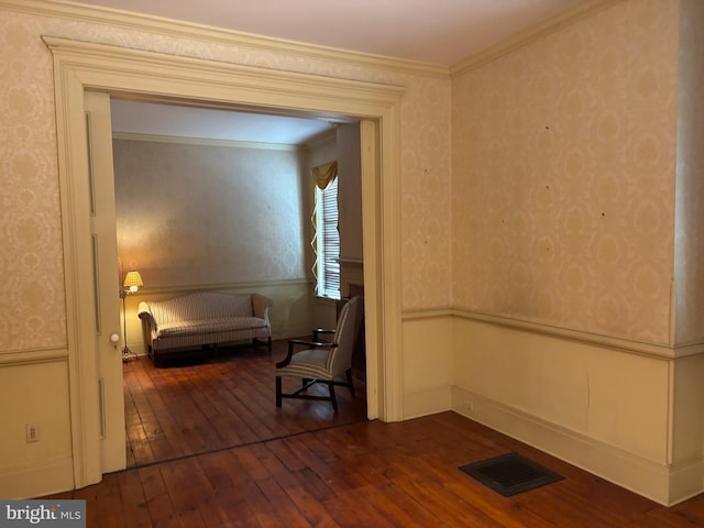 unfurnished room featuring wallpapered walls, dark wood finished floors, visible vents, and ornamental molding