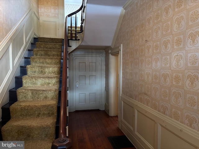 staircase featuring a decorative wall, wood finished floors, a wainscoted wall, and wallpapered walls