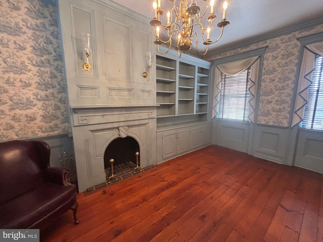 living room featuring a wainscoted wall, wallpapered walls, dark wood-type flooring, and an inviting chandelier