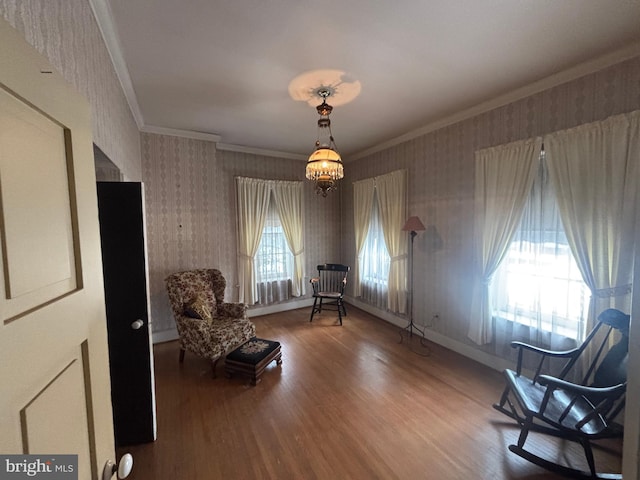 sitting room featuring a chandelier, plenty of natural light, wood finished floors, and ornamental molding