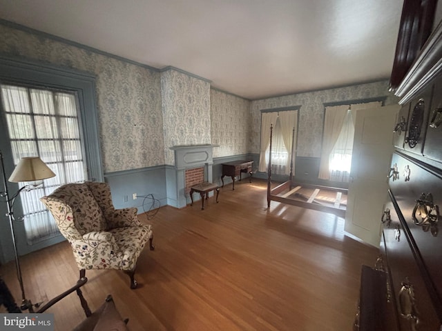 sitting room featuring wallpapered walls, wood finished floors, and a wainscoted wall