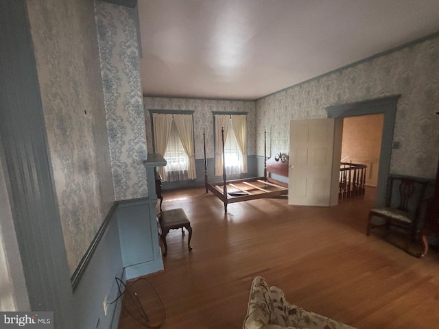 interior space with a wainscoted wall, wood finished floors, and wallpapered walls