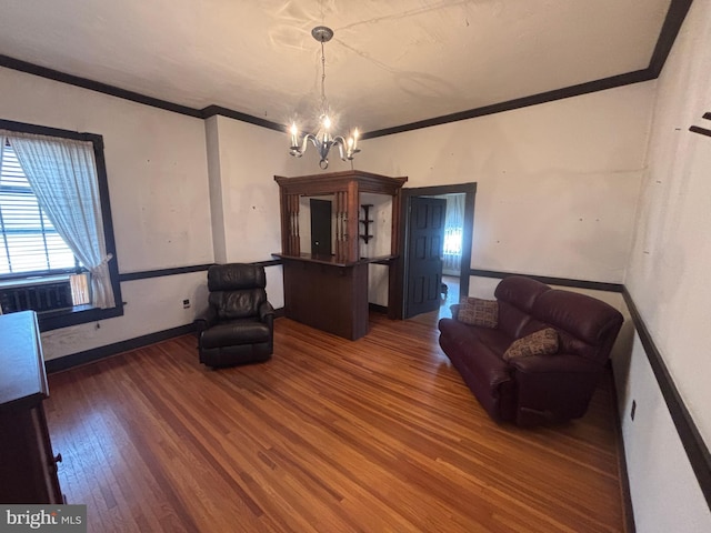 living area featuring ornamental molding, baseboards, an inviting chandelier, and wood finished floors