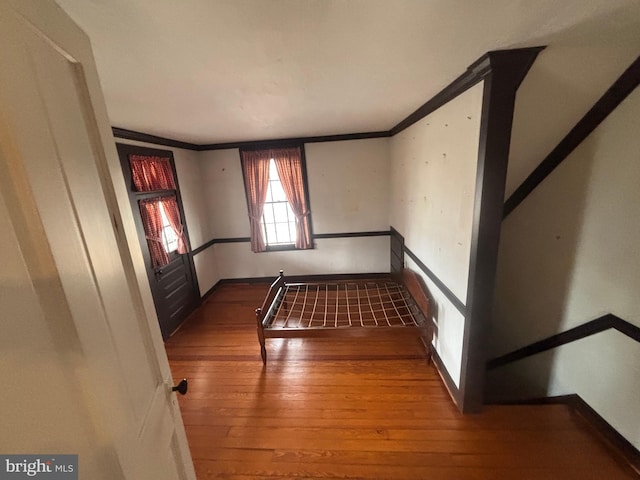 empty room with hardwood / wood-style floors, baseboards, and ornamental molding