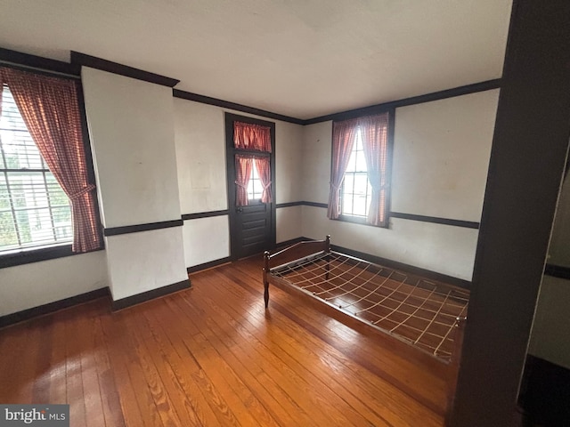 spare room featuring baseboards, wood-type flooring, and ornamental molding