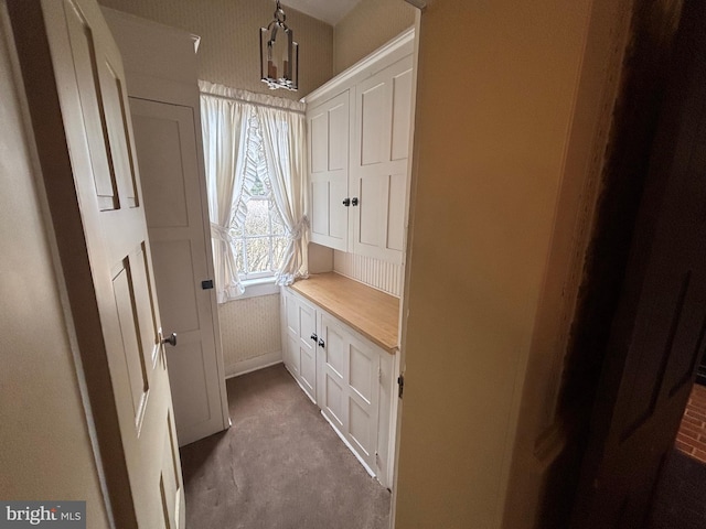 doorway featuring baseboards and a notable chandelier