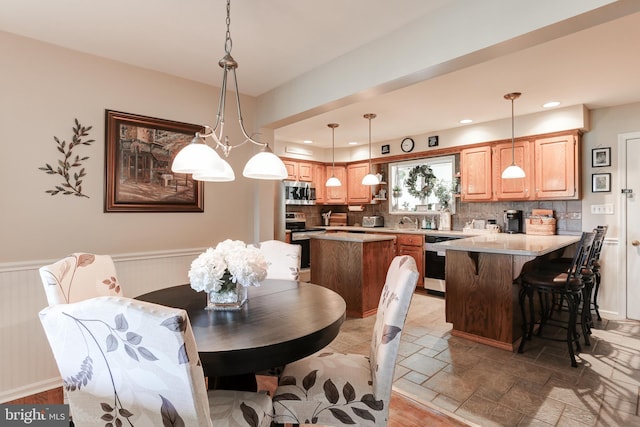 dining space with recessed lighting, a wainscoted wall, and stone finish floor