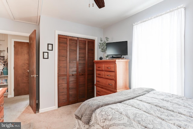 bedroom with a closet, light carpet, and a ceiling fan