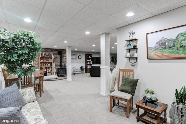 living area with a wood stove, a drop ceiling, recessed lighting, and carpet floors