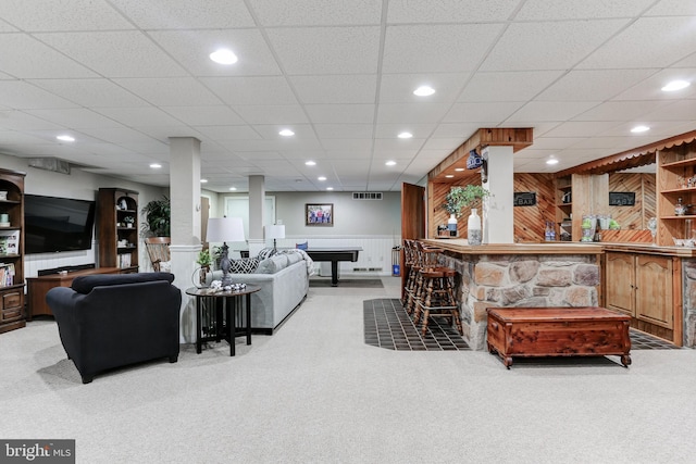 living room featuring wooden walls, a wainscoted wall, recessed lighting, a bar, and light colored carpet