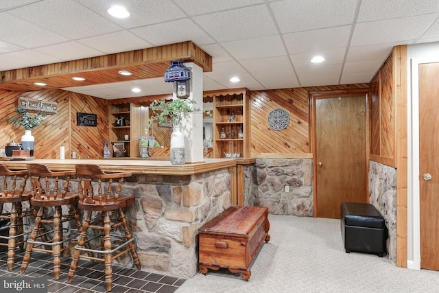 bar with bar area, carpet, recessed lighting, and wood walls