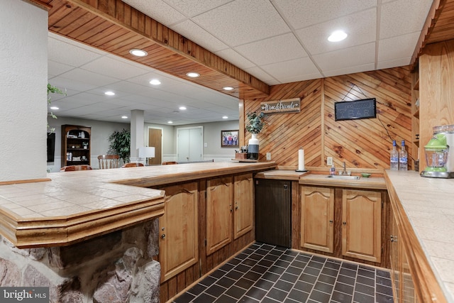 bar featuring wood walls, fridge, a paneled ceiling, and a sink