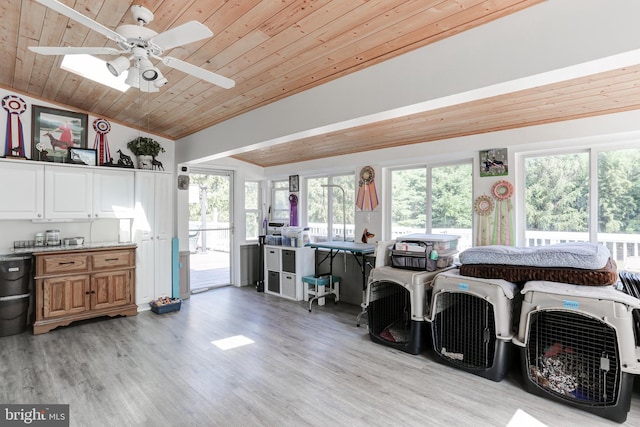 interior space with lofted ceiling, ceiling fan, light countertops, light wood-style floors, and wooden ceiling