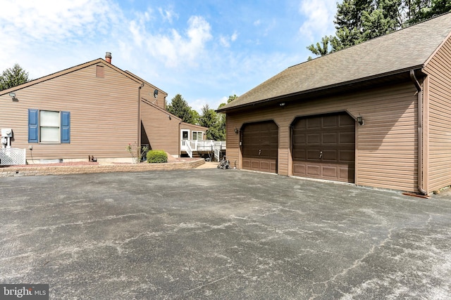 view of side of property with a shingled roof and central AC