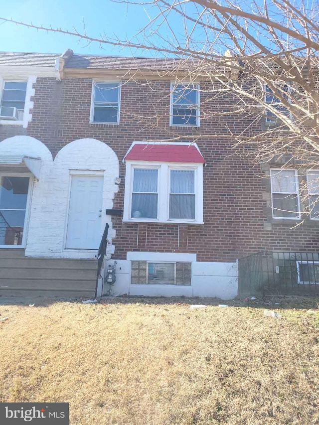 townhome / multi-family property with brick siding and a front yard