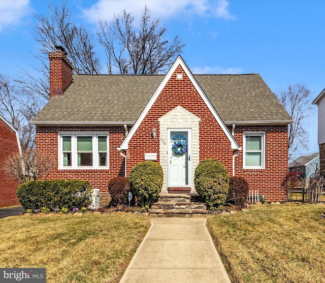 view of front of property featuring brick siding, a shingled roof, and a front lawn