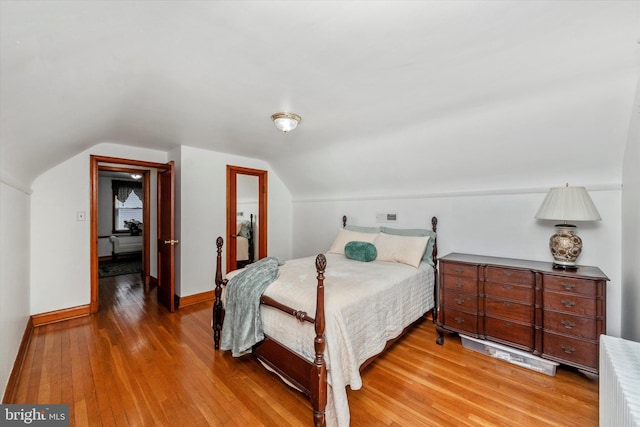 bedroom with baseboards, light wood-type flooring, and lofted ceiling