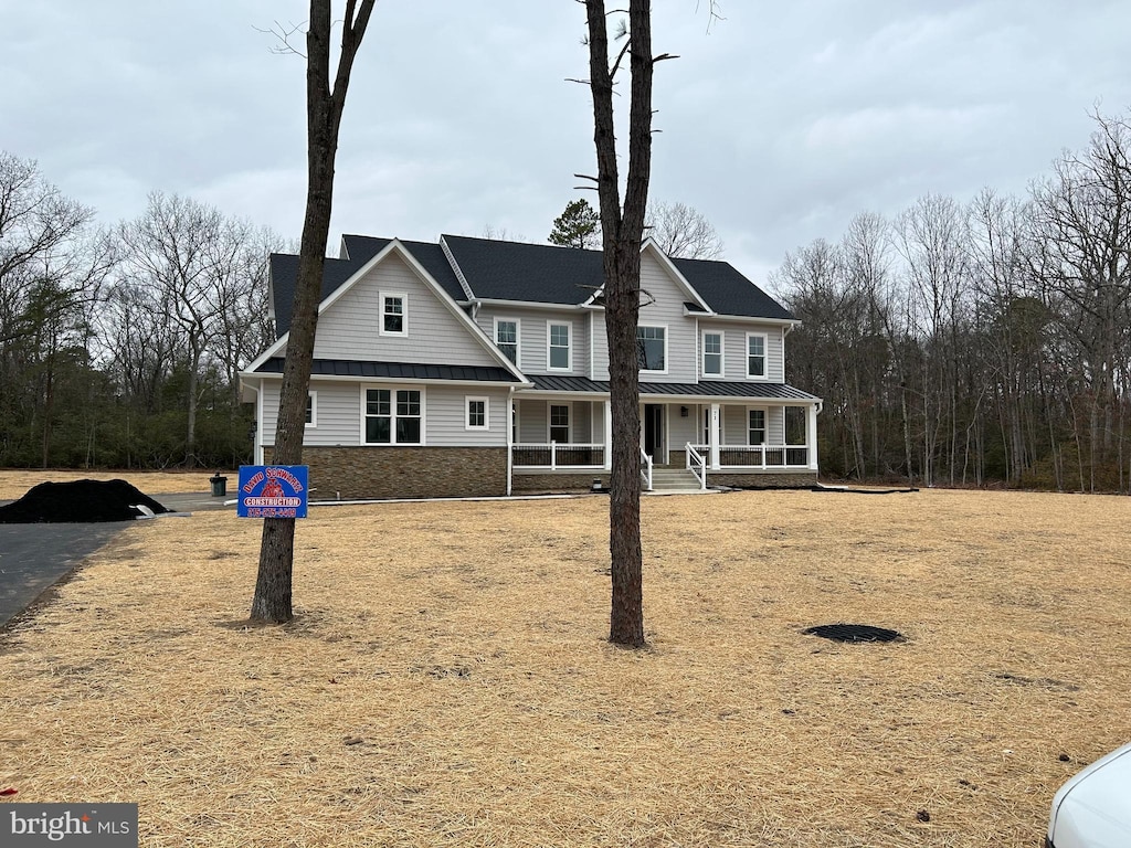 view of front of house with metal roof, stone siding, a porch, and a standing seam roof