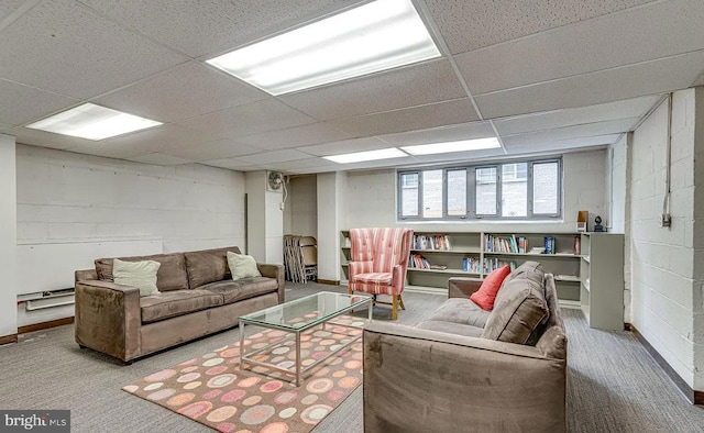 carpeted living room with a drop ceiling and concrete block wall