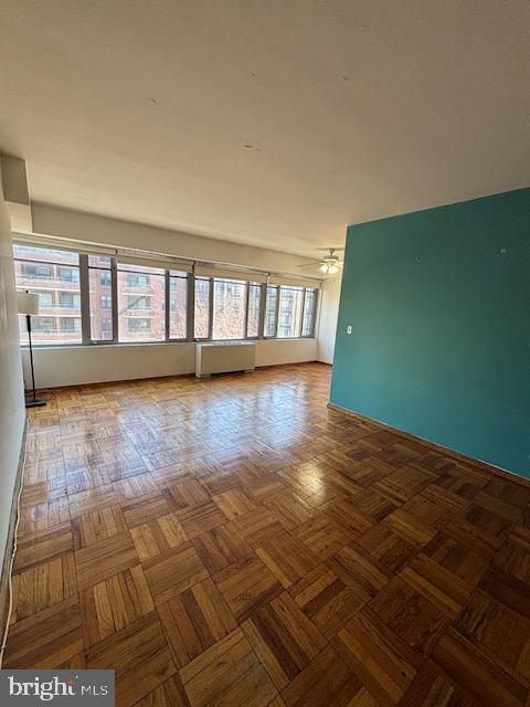 unfurnished room with a ceiling fan and radiator heating unit