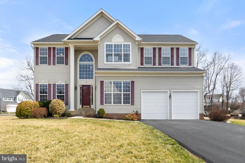 traditional home with aphalt driveway, a front lawn, and a garage