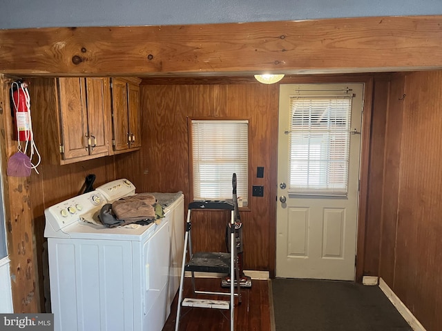 laundry area with cabinet space, wooden walls, and washing machine and dryer