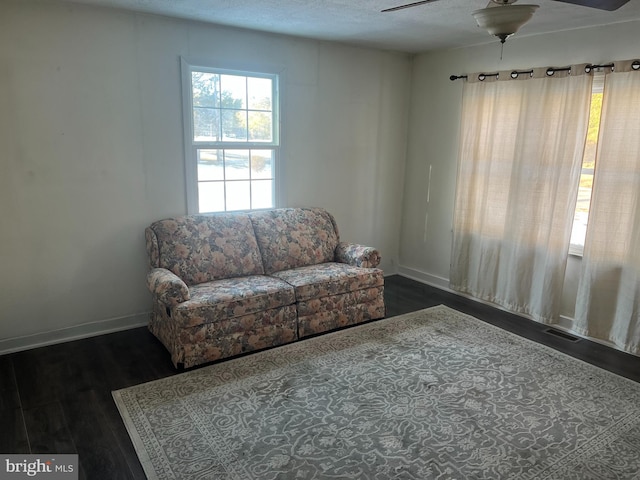 living area with wood finished floors, visible vents, baseboards, ceiling fan, and a textured ceiling