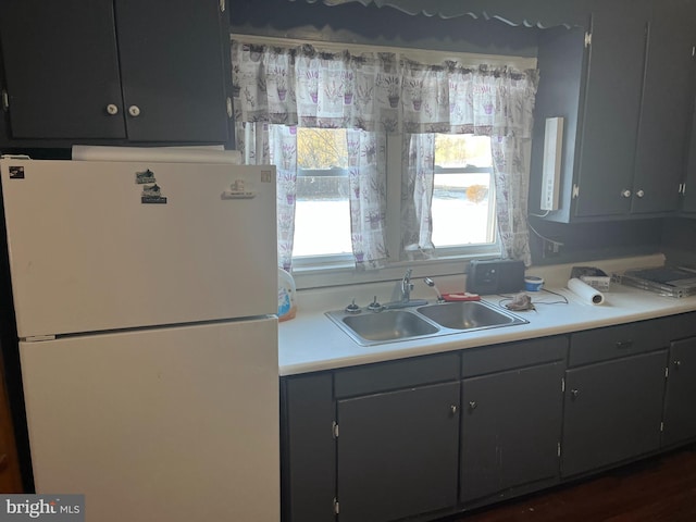 kitchen with light countertops, freestanding refrigerator, and a sink