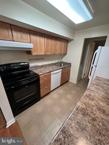 kitchen with under cabinet range hood, baseboards, white appliances, and a sink