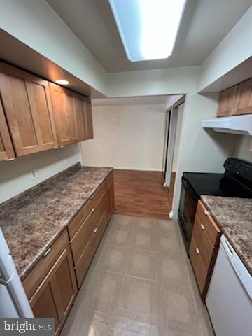 kitchen with black range with electric stovetop, under cabinet range hood, dark stone counters, white dishwasher, and light floors