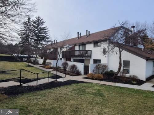 view of home's exterior with stucco siding, a lawn, a balcony, and fence