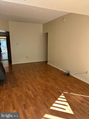 unfurnished room featuring wood finished floors and a wood stove