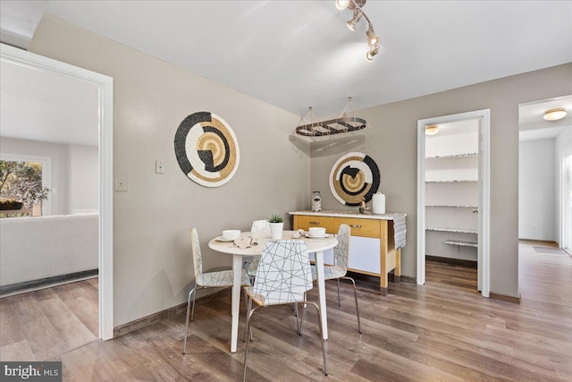dining space with light wood-type flooring and baseboards