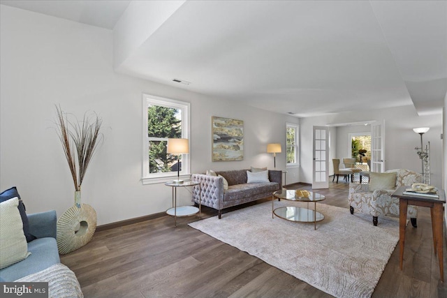 living area with a wealth of natural light, wood finished floors, visible vents, and baseboards