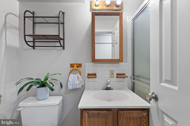 bathroom featuring a shower with shower door, vanity, backsplash, and toilet