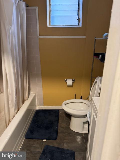 full bath with tile patterned floors, shower / bathtub combination with curtain, and toilet