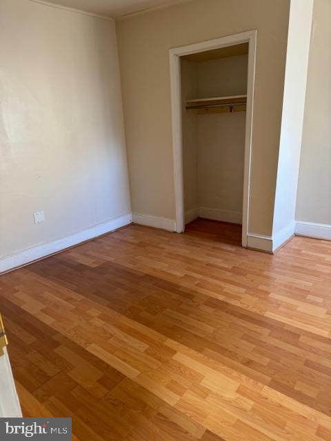 unfurnished bedroom with light wood finished floors, a closet, and baseboards