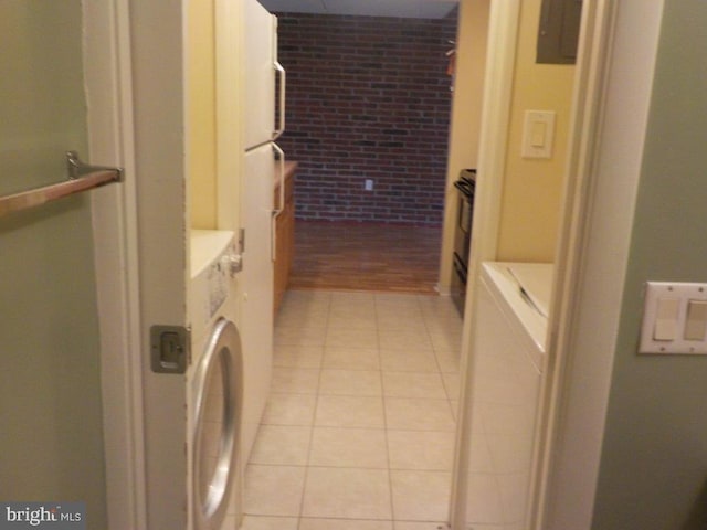 clothes washing area with light tile patterned floors and brick wall