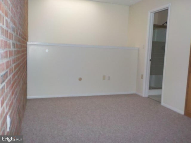 carpeted spare room with brick wall