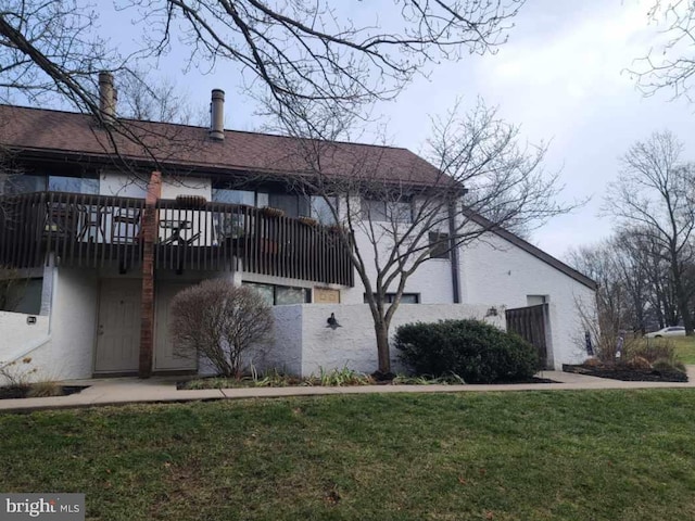 view of side of home with stucco siding and a yard