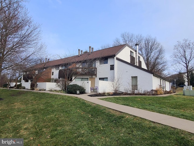 view of side of property with a yard, a balcony, and stucco siding