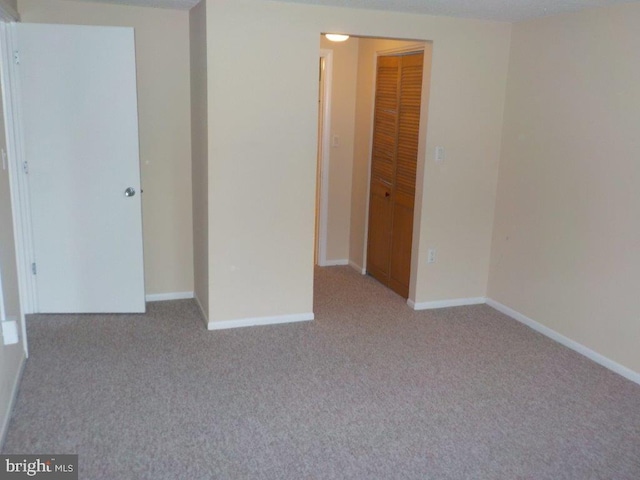 unfurnished bedroom with baseboards, a closet, and light carpet