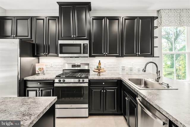 kitchen with tasteful backsplash, light countertops, dark cabinetry, stainless steel appliances, and a sink