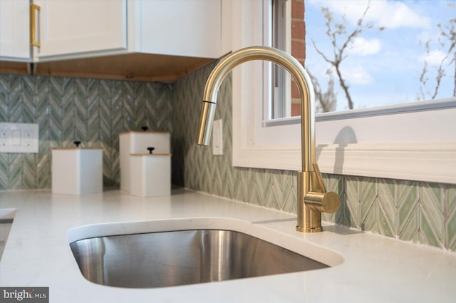 details with a sink, decorative backsplash, white cabinets, and light countertops