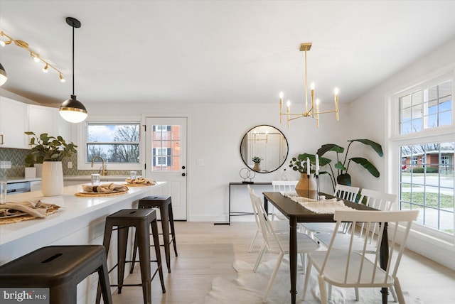 dining area with a chandelier, light wood-type flooring, and baseboards