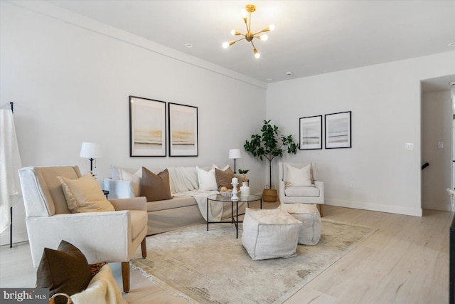 living room with light wood finished floors, a notable chandelier, and baseboards