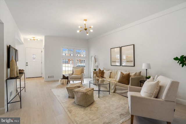 living area featuring a notable chandelier, light wood-style floors, visible vents, and baseboards