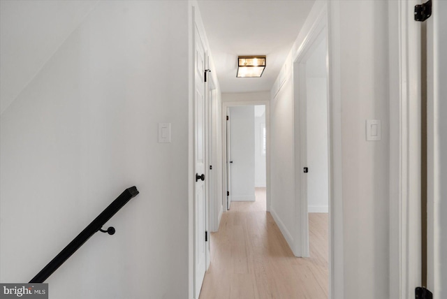 hall featuring an upstairs landing, light wood finished floors, and baseboards