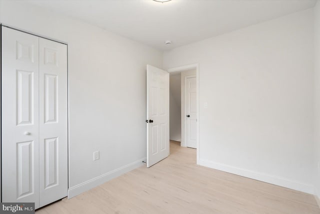 unfurnished bedroom with a closet, baseboards, and light wood finished floors