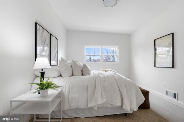 bedroom with visible vents, baseboards, and wood finished floors